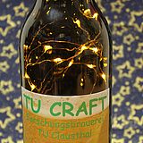 Braunglas-Bierflasche mit TU Craft Label, in der Flasche ist eine leuchtende Mini-Lichterkette