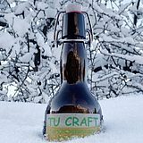 Braunglas-Bierflasche, die zur Hälfte im Schnee steckt