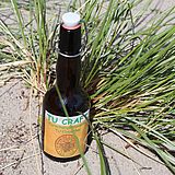 Eine Flasche Bier steht an einem Büschel Strabdgras